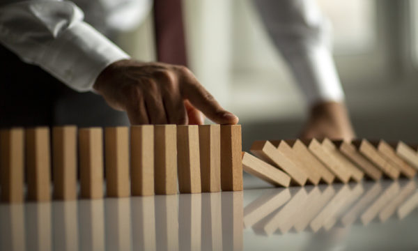Businessman Stop Domino Effect. Risk Management and Insurance Concept