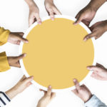 Diverse hands supporting a blank yellow round board