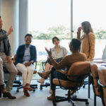 Team of five multi-ethnic employee having fun working together in an open plan office with big windows.
