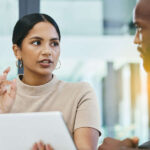 Shot of two work colleagues using a digital tablet during a business meeting at work