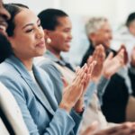 Business people, woman and team applause in conference, tradeshow and support feedback of success. Happy employees, audience and clapping in celebration, praise or winning award at seminar convention