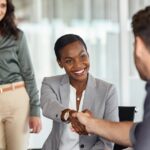 Happy black businesswoman and businessman shaking hands at meeting. Professional business executive leaders making handshake agreement. Happy business man closing deal at negotiations with african american woman.