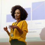 Woman entrepreneur speaking in the auditorium at the corporate training event. Woman at seminar giving a presentation.