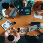 Top down view of business woman explain and present financial chart. Diverse group discuss and listen presentation about stock market statistic at meeting table with investment graph. Convocation.