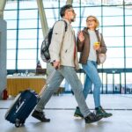 Cheerful mature couple of passengers with luggage at the train station