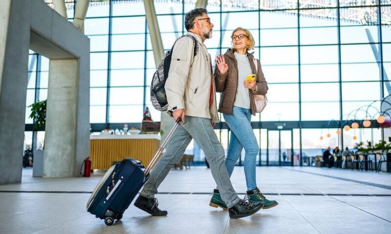 Cheerful mature couple of passengers with luggage at the train station