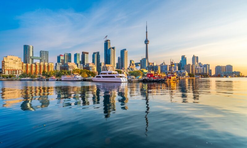 Toronto, Canada city skyline and tower on Lake Ontario at dawn.