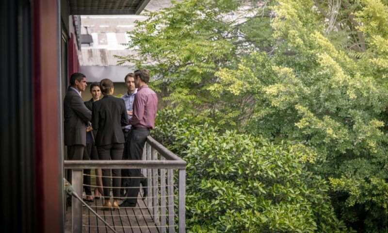Confident business colleagues discussing on balcony at office. Male and female executives are planning strategy outdoors. They are wearing formals.