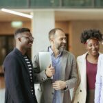 Group of Diverse Coworkers Standing at the Office Corridor and Smiling while Having an Informal Conversation