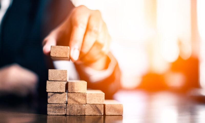 plan and strategy in business.risk concept.hand of man has piling up and stacking a wooden block.Businessman Building The Success.