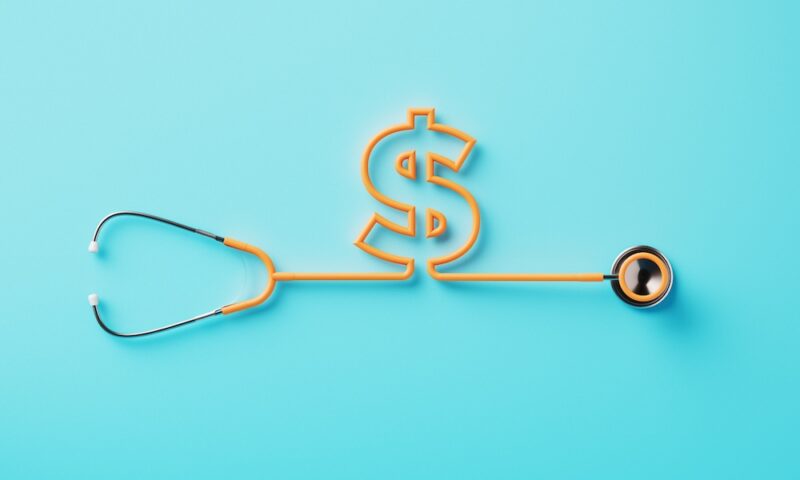 Orange stethoscope forming a dollar sign on blue background.