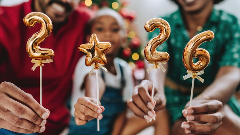 Festive family celebrating the new year at home, holding golden balloons with the numbers 2026. Christmas tree and holiday decorations in the background, joyful and warm atmosphere. Concept of family togetherness, holidays, festive season, new beginnings, 2026 celebration