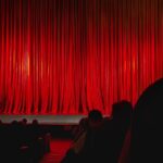 Red Theater Curtain. Closed red theater curtain illuminated by warm stage lights before performance begins. Concept of anticipation, stage performance, entertainment event