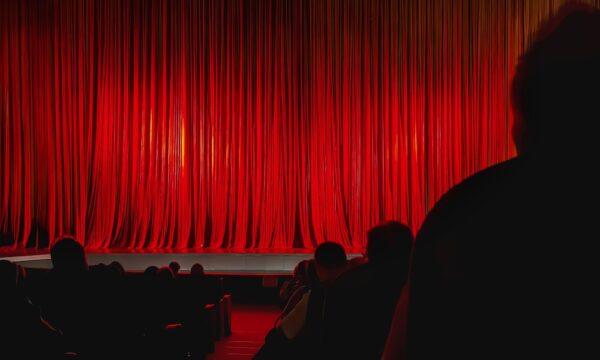 Red Theater Curtain. Closed red theater curtain illuminated by warm stage lights before performance begins. Concept of anticipation, stage performance, entertainment event