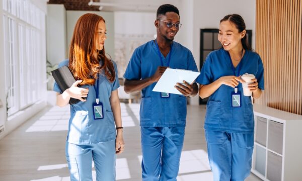 Young healthcare colleagues walking and talking at hospital corridor