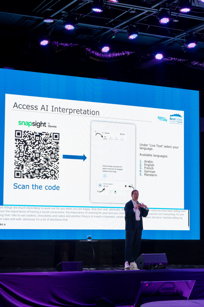 Conference speaker in front of a slide showing how attendees can access AI interpretation of the sessions.