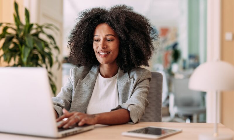 Elegant businesswoman sitting in her office and using laptop.